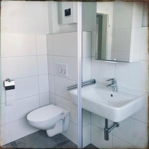 a white bathroom with a toilet and a sink at Schöne Penthousewohnung mit Weitblick in Arnsberg