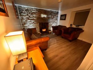 a living room with couches and a stone fireplace at Carnmhor, Isle of Skye - Stunning 242 year old cottage on its own sea shore! in Breakish