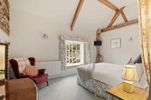 a bedroom with a bed and a chair and a window at Horseshoe Cottage Farm with Hot Tub in Leicester