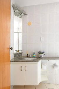 a white kitchen with a sink and a mirror at Quarto de Casal em Apartamento - Belo Horizonte - Buritis in Belo Horizonte