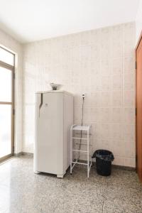 a white refrigerator in a room with a stool at Quarto de Casal em Apartamento - Belo Horizonte - Buritis in Belo Horizonte