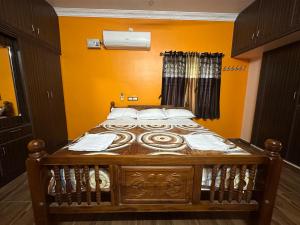 Cama de madera en habitación con paredes de color naranja en Jothi Cottage -HomeStay, 