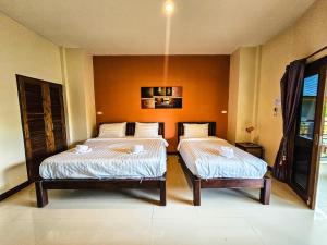 two beds in a room with orange walls at Saphli Villa in Chumphon