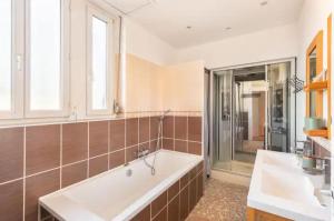 a bathroom with a tub and two sinks and a shower at Peyerimhoff Colmar - 3 Chambres - 8 Pers - Clim in Colmar