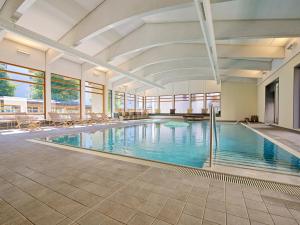 a large swimming pool with chairs in a building at Schweizerhof Ferienwohnungen Lenzerheide 2 in Lenzerheide