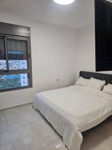 a white bedroom with a large bed with a window at Elegant 3 bedroom Ocean view Condo in Kiryat Yam in Qiryat Yam +12 photos