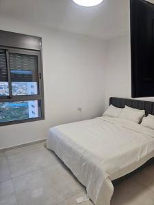 a white bedroom with a large bed with a window at Elegant 3 bedroom Ocean view Condo in Kiryat Yam in Qiryat Yam