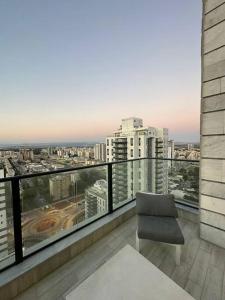 a balcony with a chair and a view of a city at Elegant 3 bedroom Ocean view Condo in Kiryat Yam in Qiryat Yam