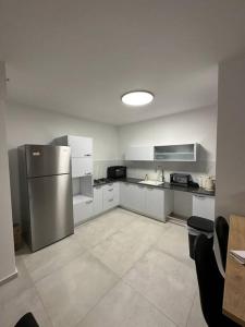 a kitchen with a stainless steel refrigerator and white cabinets at Elegant 3 bedroom Ocean view Condo in Kiryat Yam in Qiryat Yam