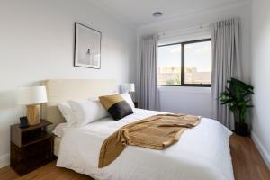 een witte slaapkamer met een bed en een raam bij Luxury 4 Bedroom Beach House with Ocean Views and Smart Technology in Warrnambool