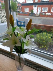 eine Vase voller weißer Blumen im Fenster in der Unterkunft Tower Views 2 Bedroom House with Private Parking in Blackpool