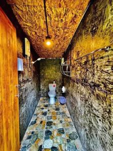 a bathroom with a toilet in a stone wall at Bridge Hill Cafe Glamping in Khao Sok