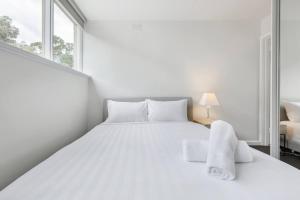 Un dormitorio blanco con una cama blanca y una ventana en Bright and Modern Space with a Balcony and Parking en Melbourne