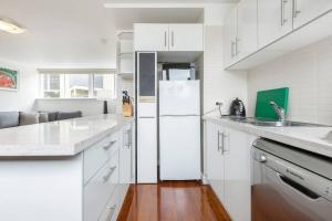 a white kitchen with white cabinets and a refrigerator at Bright and Modern Space with a Balcony and Parking in Melbourne
