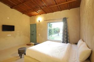 Bhundsi的住宿－Brahmaputra cafe and resort，一间卧室设有一张大床和一个窗户。