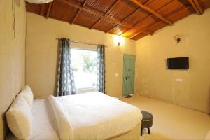 a bedroom with a white bed and a window at Brahmaputra cafe and resort in Bhundsi