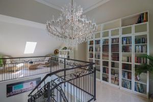 a staircase with a chandelier and bookshelves at Naturtalente Villa in Sankt Johann in der Haide