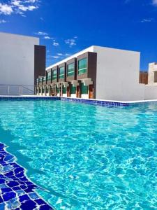 a large swimming pool in front of a building at Apartamentos Villa dos Diamantes in Porto Seguro