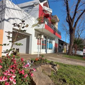 un edificio bianco con un balcone rosso e fiori di AltoRojo a Villa Elisa