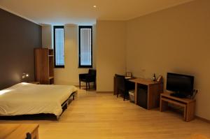 a bedroom with a bed and a desk and a television at Boardhousing in Leuven