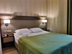 MisailovoにあるKA Royal Hotel BOUTIQUE - КА Роял Бутик Отельのベッドルーム1室(大型ベッド1台、緑の毛布付)