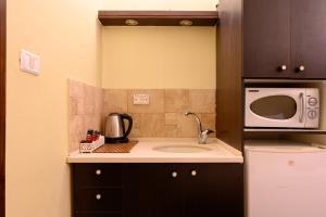 a small kitchen with a sink and a microwave at My Place in the Colony in Zikhron Ya'akov