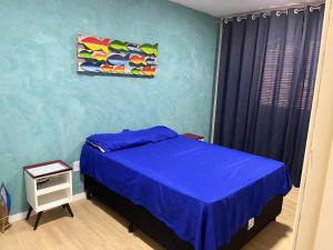 um quarto com uma cama e uma parede azul em Bela casa em condominio de frente a cachoeira em Paraty
