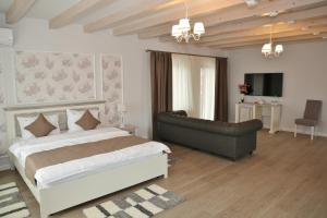 a bedroom with a large bed and a couch at Domeniile Panciu Winery & Resort in Sîrbi