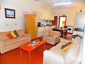 a living room with couches and a table and a kitchen at Shark shacks in Mossel Bay