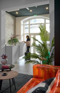 a woman standing at a counter in a room with plants at Butik Life Hotel & Apartments in Budapest