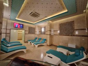 梅爾辛的住宿－Royal Mersin Otel，一间设有蓝色和白色椅子和电视的等候室