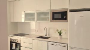 uma cozinha branca com um lavatório e um micro-ondas em Afonso Galo Guest Apartments IV em Almada