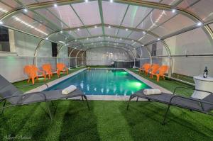 an indoor pool with orange chairs and a swimming pool at וילת שלוות ענהאל in Sifsufa