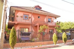 ein rosafarbenes Haus mit einem Balkon und Bäumen in der Unterkunft Vila Alexandru in Eforie Nord