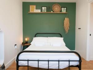 ein Schlafzimmer mit einem Bett mit einer grünen Wand in der Unterkunft Pass the Keys - Beautiful designer Maisonette with Garden and BBQ in London