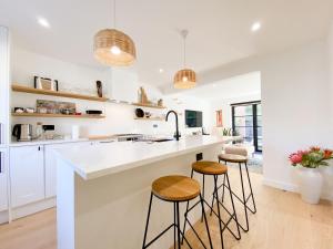 a kitchen with white counter tops and stools at Pass the Keys - Beautiful designer Maisonette with Garden and BBQ in London