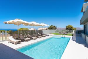 a swimming pool with lounge chairs and umbrellas at Heliades Residence in Kounoupidhianá