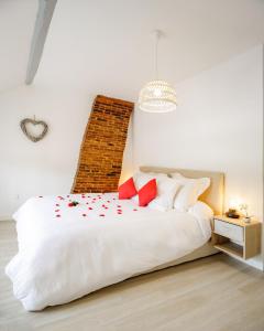 a bedroom with a white bed with red pillows at Escapade au Cocon des Plaisirs Secrets Spa &Sauna 