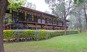 - un bâtiment avec un balcon et des buissons en face dans l'établissement Kongoni Camp, à Nanyuki