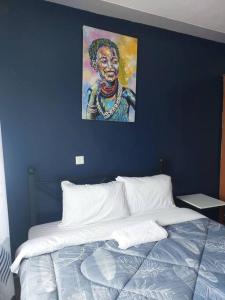 eine blaue Wand mit einem Gemälde über einem Bett in der Unterkunft SADE in Naivasha