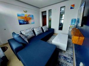 ein Wohnzimmer mit einem blauen Sofa und einem Tisch in der Unterkunft SADE in Naivasha