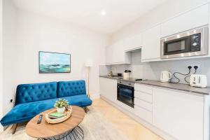 a living room with a blue couch and a kitchen at The Solo Haven 20 Min to Central in London