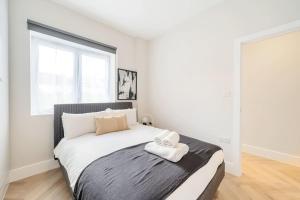 Un dormitorio blanco con una cama con una toalla. en The Solo Haven 20 Min to Central, en Londres