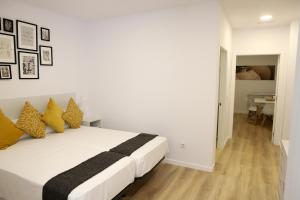 a white bed with yellow pillows in a bedroom at VUT PEDRO LUXURY in Padrón