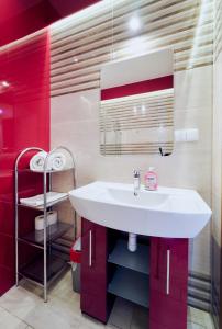 La salle de bains est pourvue d'un lavabo blanc et de murs rouges. dans l'établissement Marel- Apartament Rubinowy sauna Polanica Zdrój, à Polanica-Zdrój