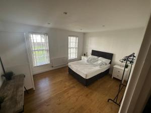 a bedroom with a bed and two windows at Calverley House Apartments in Bishops Stortford