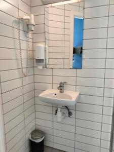 a white bathroom with a sink and a mirror at Sjøgløtt Gjestgiveri in Kristiansand