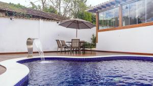 uma piscina com uma mesa e um guarda-sol em Flat com Piscina no Centro de Tiradentes em Tiradentes