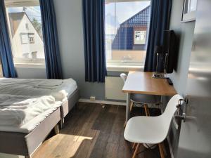 Schlafzimmer mit einem Bett und einem Schreibtisch mit einem TV in der Unterkunft Sjøgløtt Gjestgiveri in Kristiansand