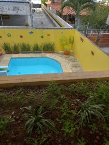 a swimming pool in a yard with a yellow wall at Pousada Aconchego do Tambaú in João Pessoa
